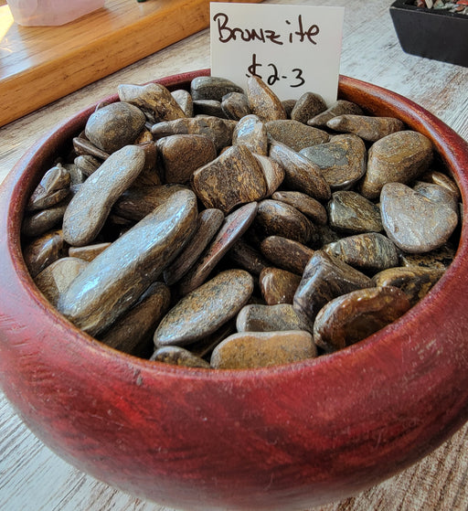 Bronzite tumbled stones showcasing a beautiful greenish brown color, known for their protective and grounding properties, perfect for balancing mind, body, and soul.