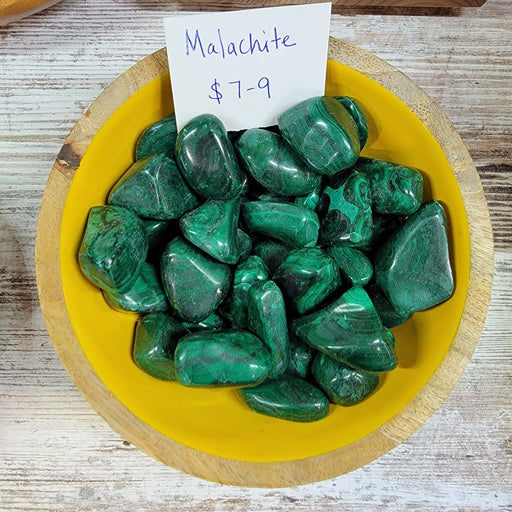 Close-up of polished Malachite tumbled stones showcasing their vibrant green color and unique patterns. Ideal for crystal healing and decoration.