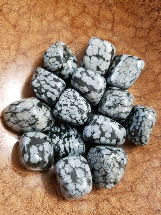Tumbled stones featuring Snowflake Obsidian Tumbled, showcasing its unique black color with white dots, symbolizing purity and balance for body, mind, and spirit.