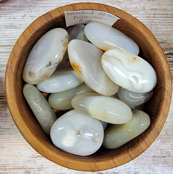 Beautiful Banded Agate Palm Stone showcasing grey hues with bands of white and brown stripes, known for providing strength, protection, and grounding energy.