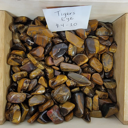 Tigers Eye tumbled stones showcasing beautiful amber to brown color variations, known for their properties of courage, strength, and good luck.